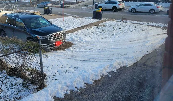 Car parked on a snowy lawn from infuriating neighbors.