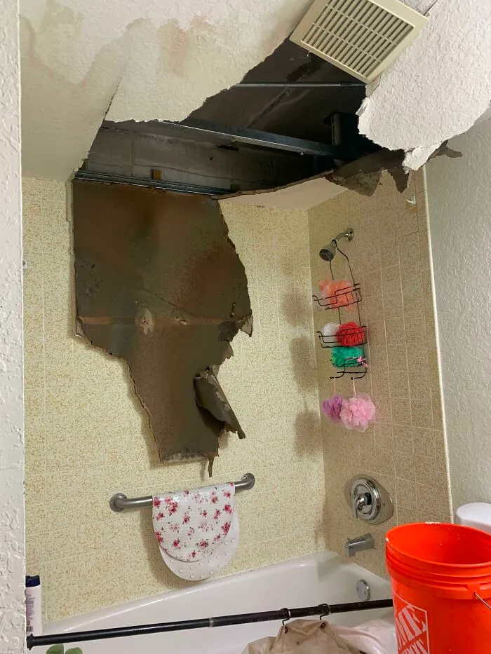 Bathroom with collapsed ceiling and wall damage caused by infuriating neighbors above.