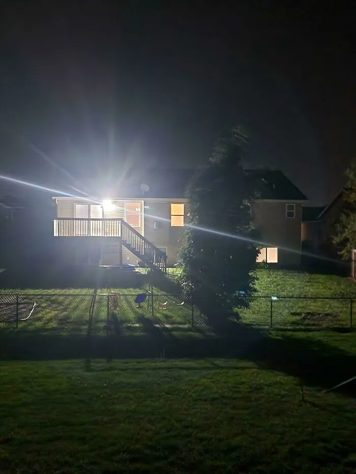 Bright outdoor floodlights shining brightly into a backyard from infuriating neighbors at night.