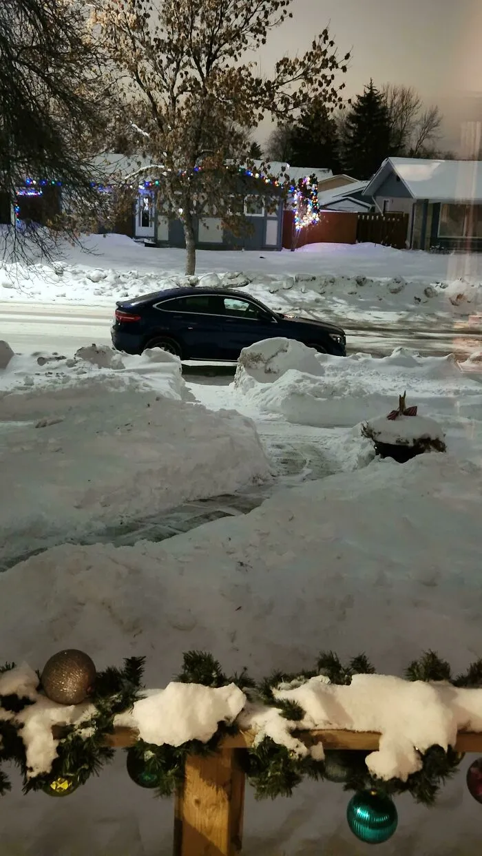 Dark blue car parked across a snow-covered driveway, showing how infuriating neighbors can create inconvenience