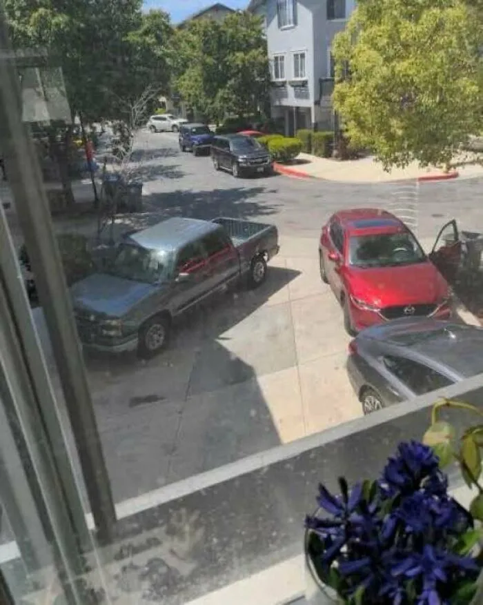 View from window of vehicles parked improperly on driveway and street, depicting bad infuriating neighbors behavior