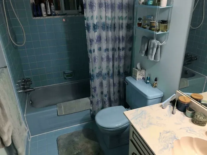 Vintage blue bathroom with floral shower curtain and matching tiles and fixtures