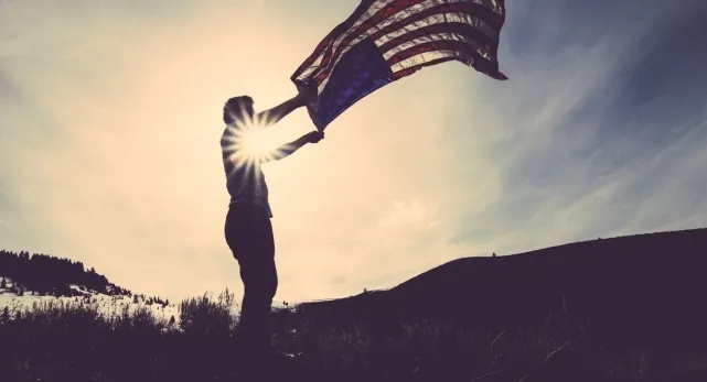 Silhouette of a person holding the United States flag against the sun in a general knowledge quiz theme