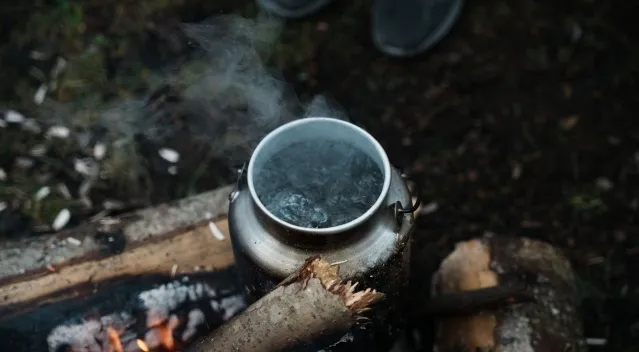 Water boiling in a metal pot over a campfire illustrating the boiling point of water