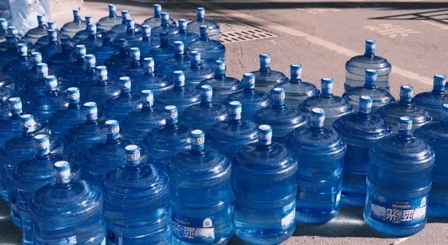 Multiple large blue water jugs, representing measurements like quarts in a gallon.