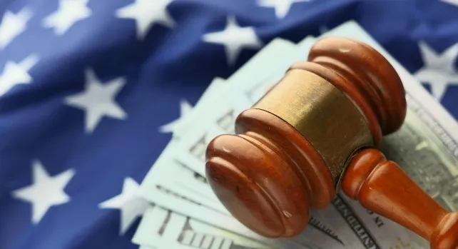 Wooden gavel on dollar bills and an American flag for a US Supreme Court question.