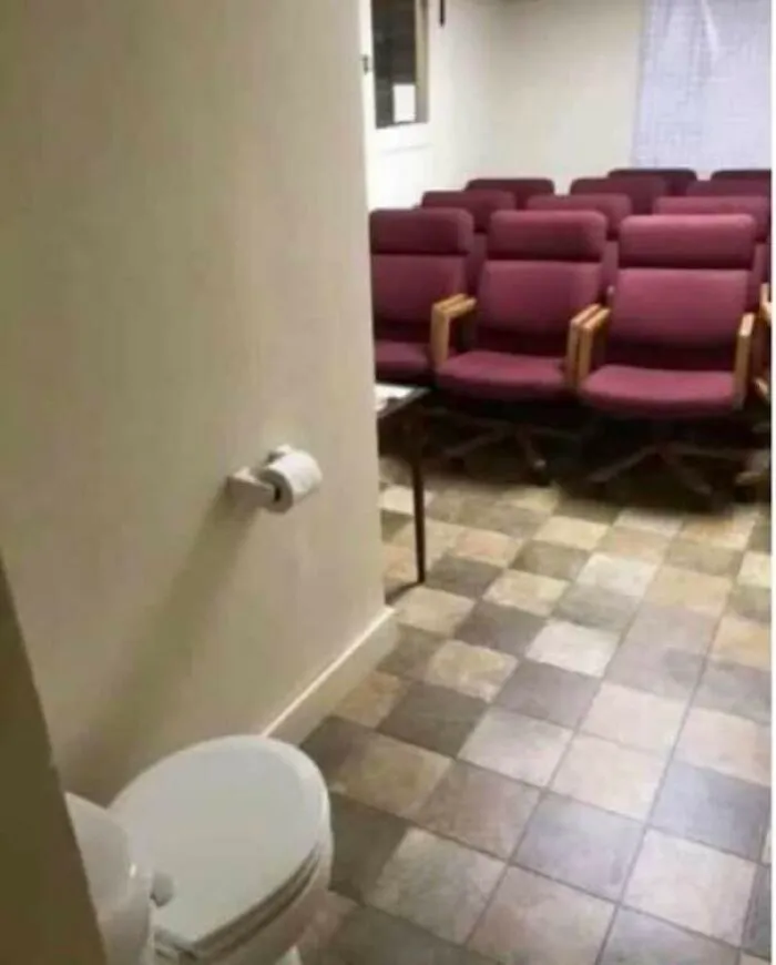 Toilet placed inside a conference room with seating and no privacy