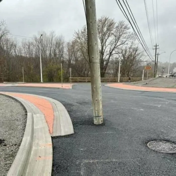 Newly paved road with an awkwardly placed utility pole in the middle