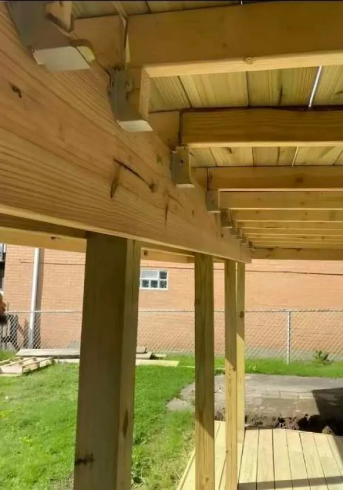 Poorly constructed wooden deck with misaligned support beams and posts