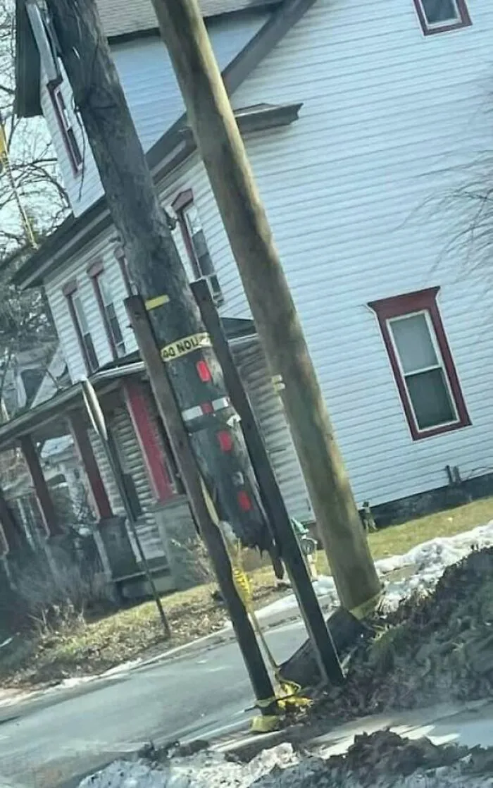 Construction fail showing uneven utility poles poorly secured near a residential street