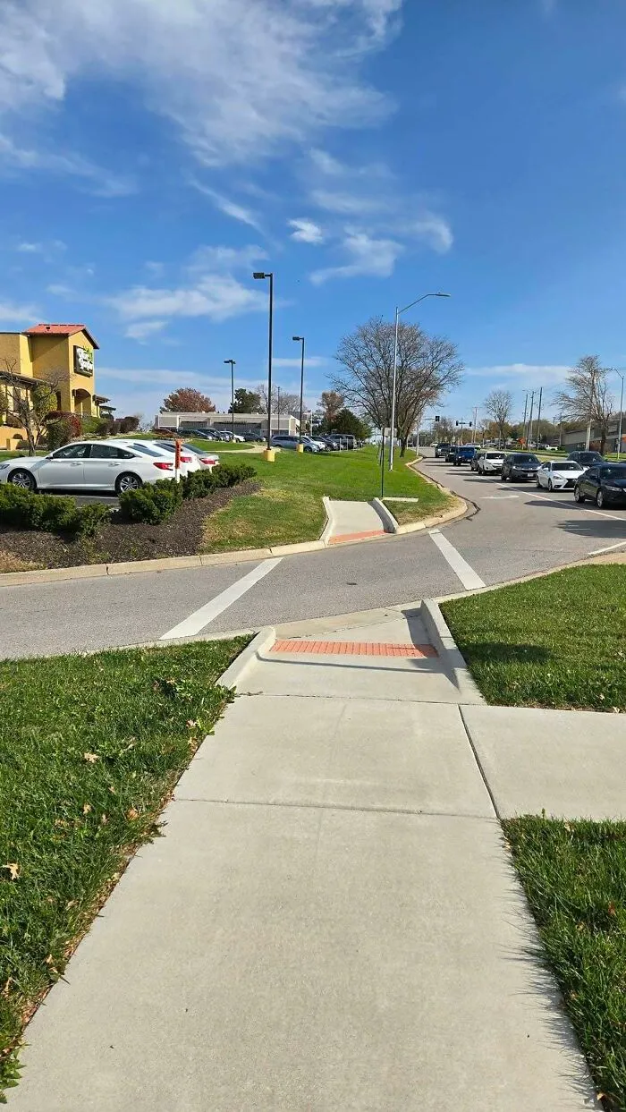 Sidewalk construction fail with impractical pedestrian ramps leading to grass