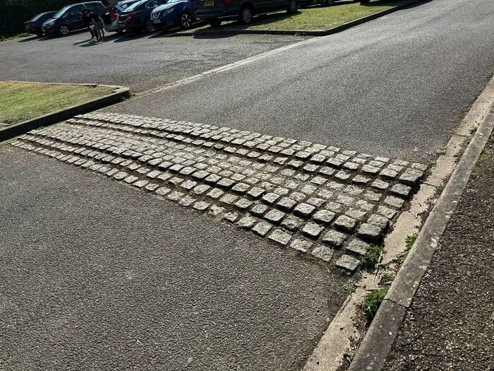 Cobblestone speed bump randomly placed across an asphalt road, a funny construction fail.