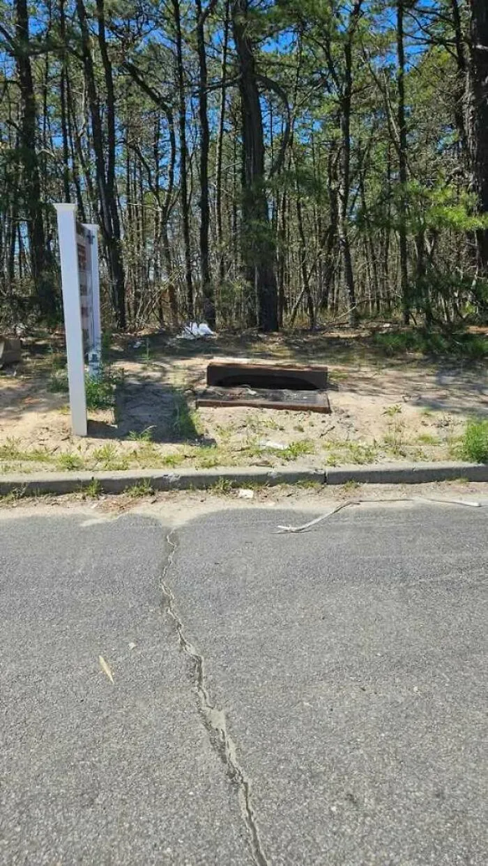 A storm drain placed completely off the road on dirt, showing funny construction fails.
