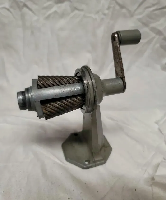 Old-fashioned metal hand-crank meat grinder on white background