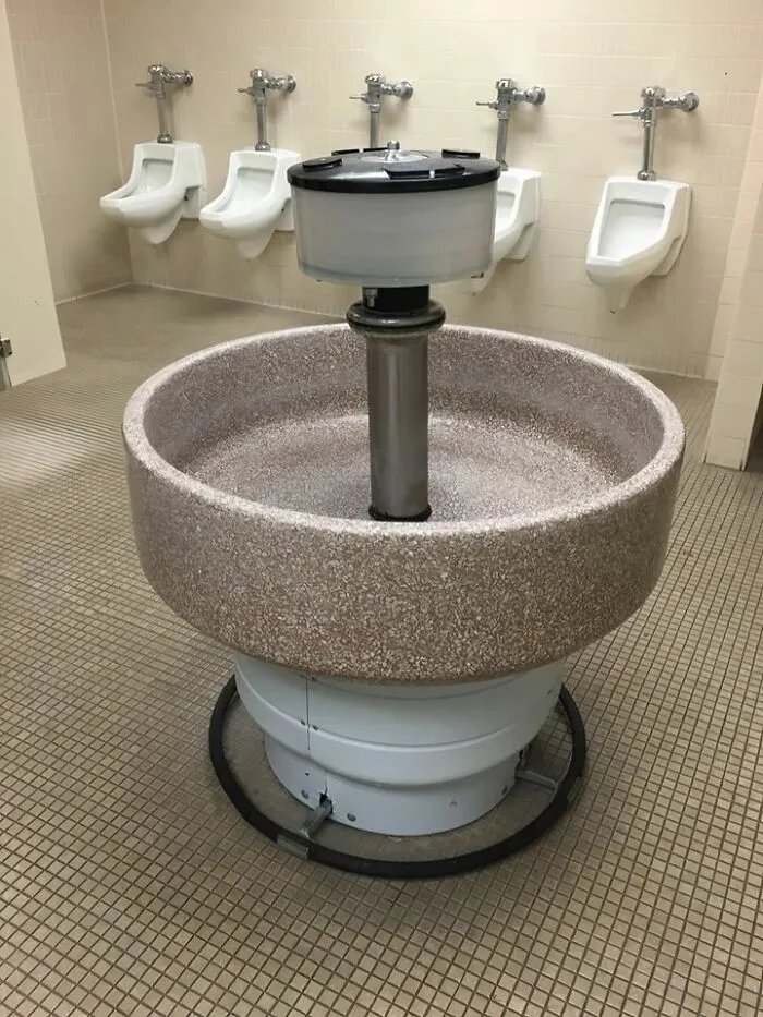 Old public restroom with vintage circular multi-user sink and urinals