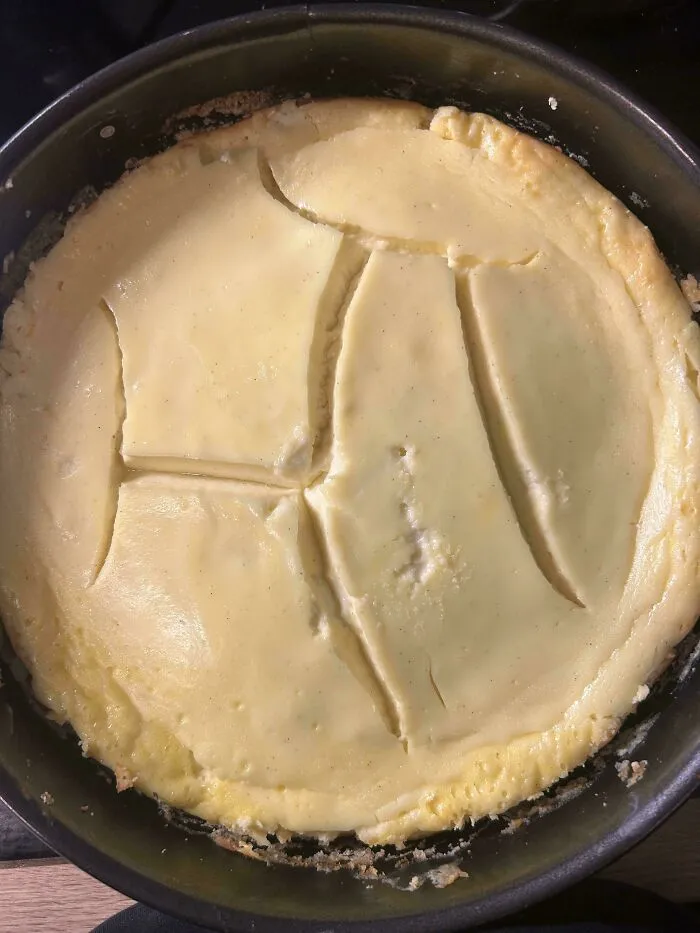 A cracked baked cheesecake inside a round springform pan as a classic baking fail.