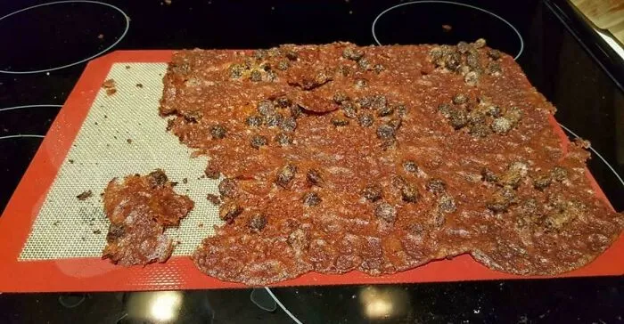 Flat burnt cookies merged together on silicon mat illustrating baking fail