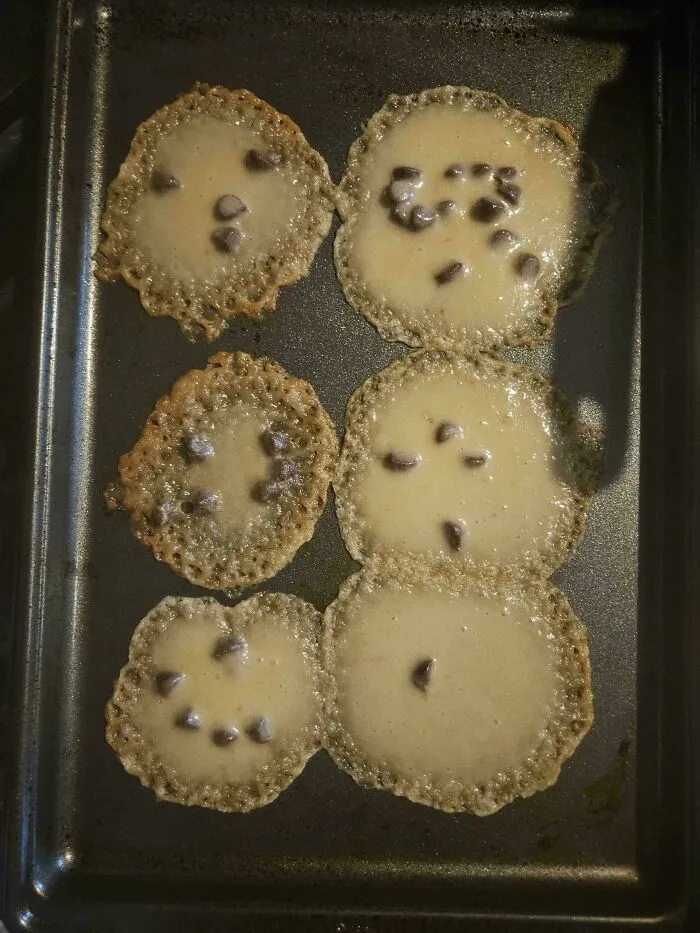 Thin and spread out chocolate chip cookies melted into flat, lace-like puddings on a baking tray, a total r/bakingfail.