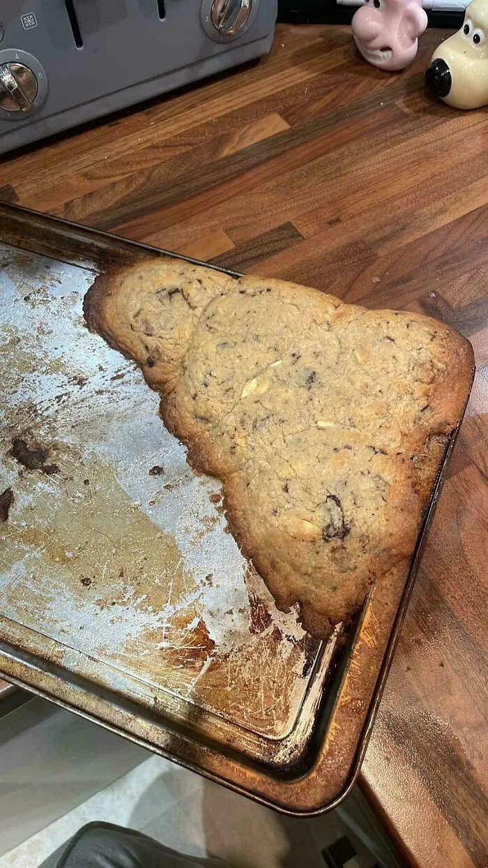 One huge merged chocolate chip cookie covering half the baking sheet in this funny r/bakingfail photo.