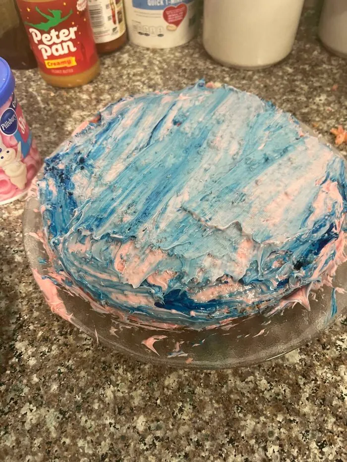 Roughly frosted cake with blue and pink icing as a baking fail.