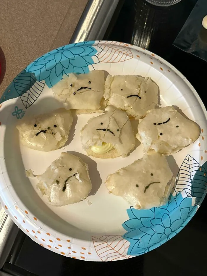 Cracked cookies on a paper plate drawn with sad faces as a funny bakingfail.