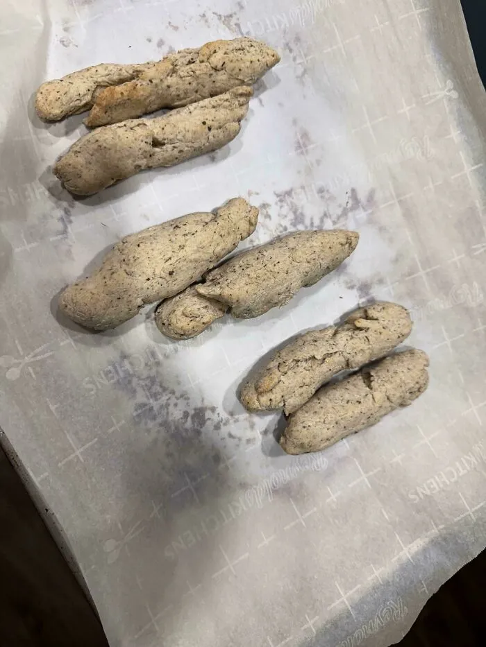 A baking fail showing pale, misshapen dough logs lined up on parchment paper.