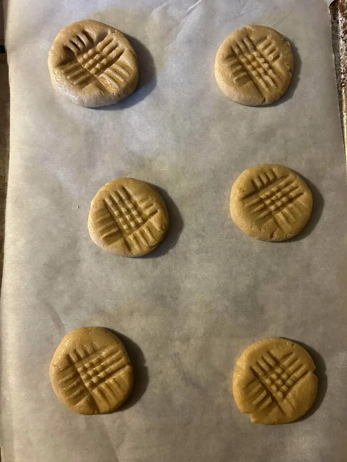 Raw peanut butter cookie dough balls stamped with a fork before baking fail.