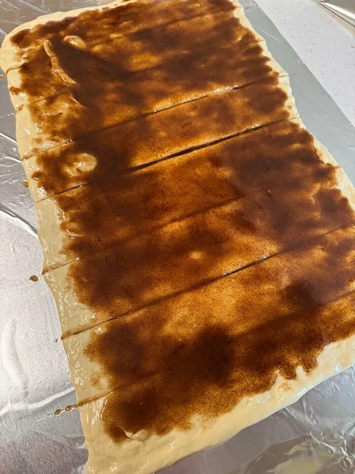 Unrolled dough covered in brown cinnamon sugar, an intermediate step in a baking fail recipe