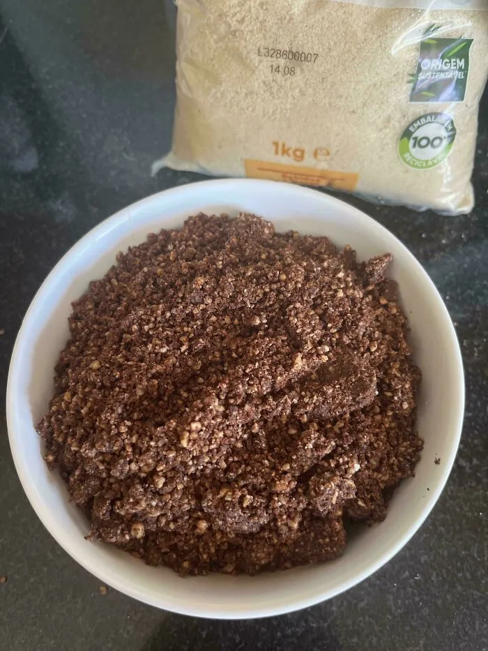Crumbled dark brown mixture in a white bowl, resulting from a baking fail