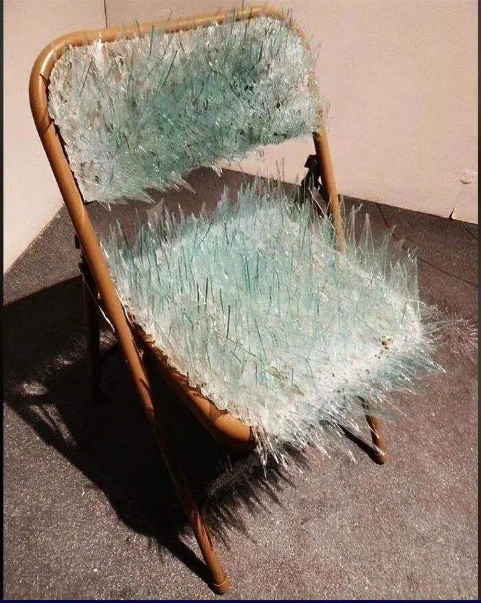 A folding chair covered in sharp, dangerous glass shards representing cursed images