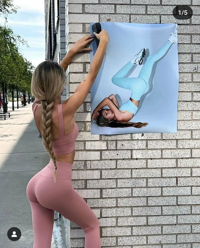 Photo of woman posting distorted fitness image on street wall with leg raised