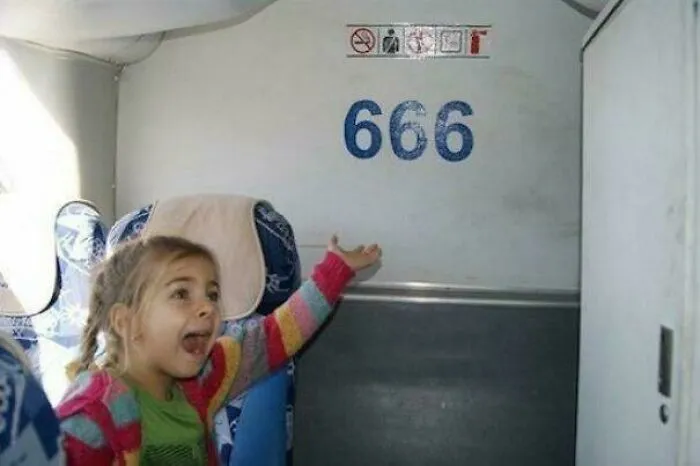 A young girl gesturing excitedly toward the number 666 printed on a wall, capturing a moment among cursed images.