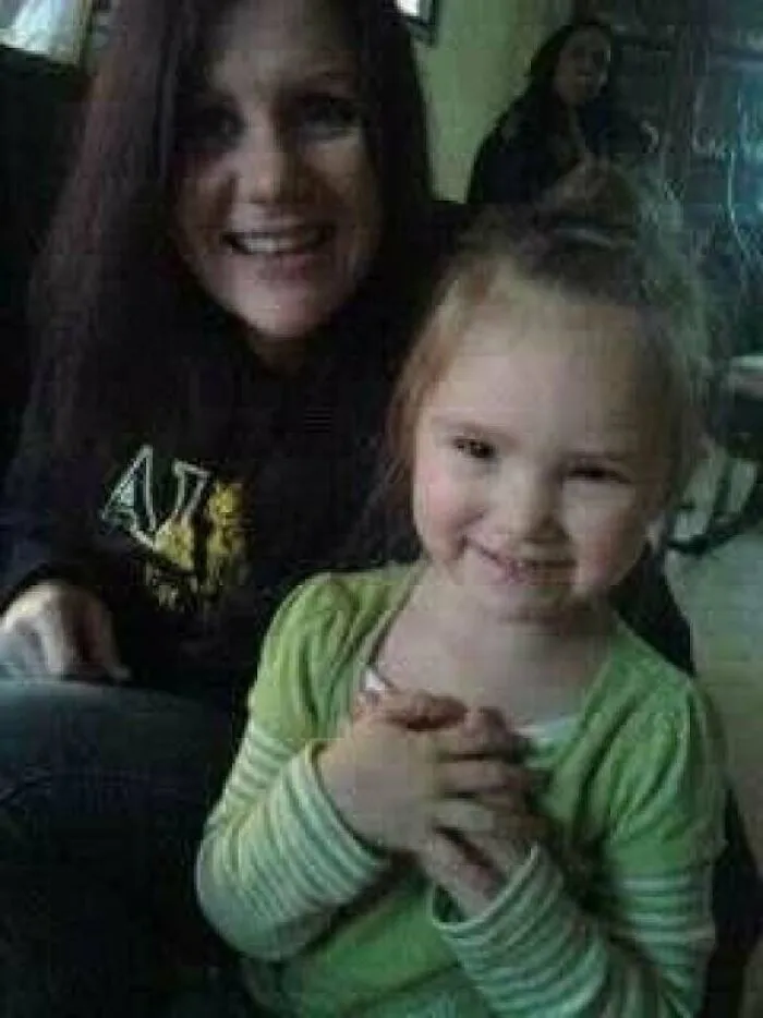 A smiling woman and child with a dark background figure, capturing creepy photos that lack logical explanation.