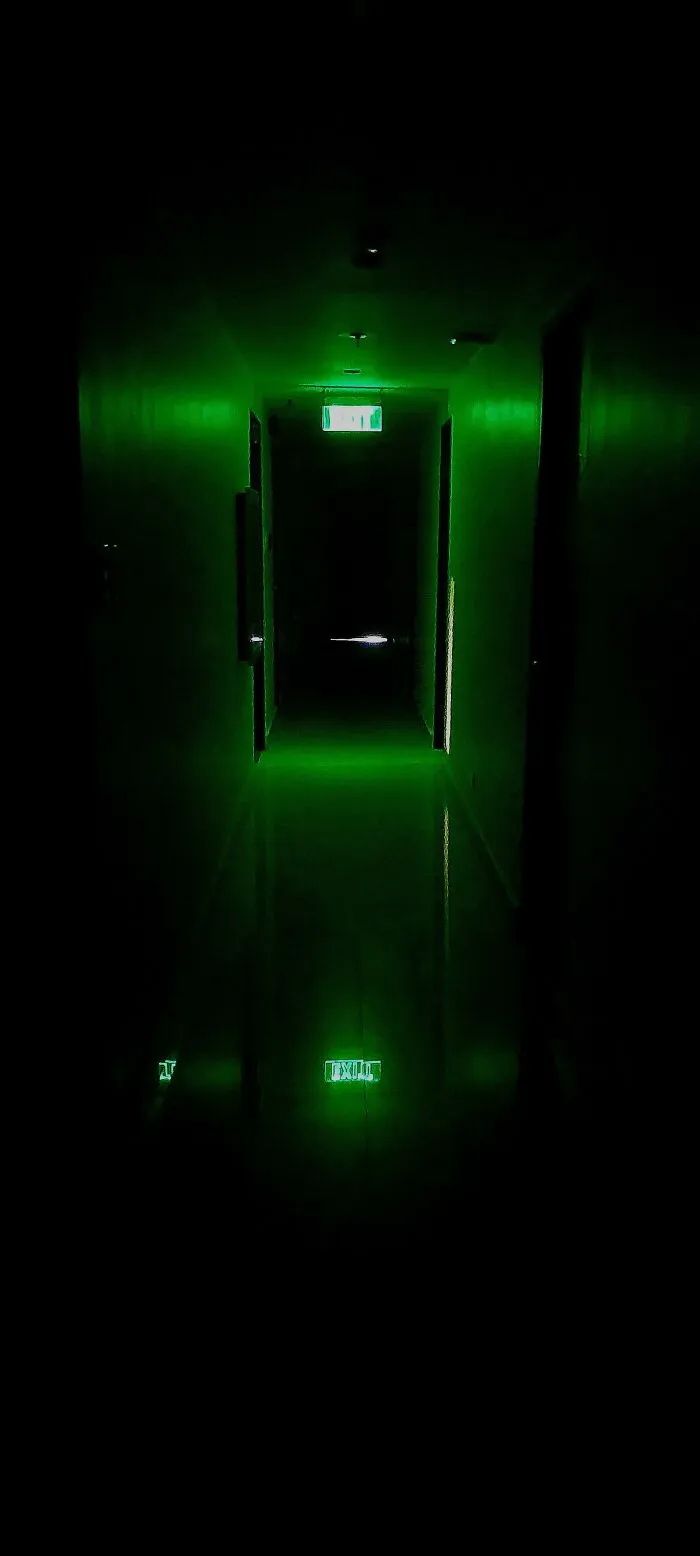 A glowing green illuminated dark hallway giving off a vibe of cursed images.