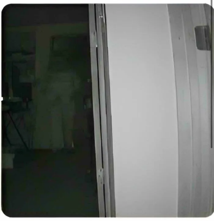 An eerie shadow figure standing in a dark doorway, captured in creepy photos.