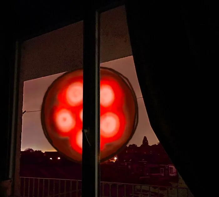 Glowing red orb seen through a window night view as featured in creepy photos