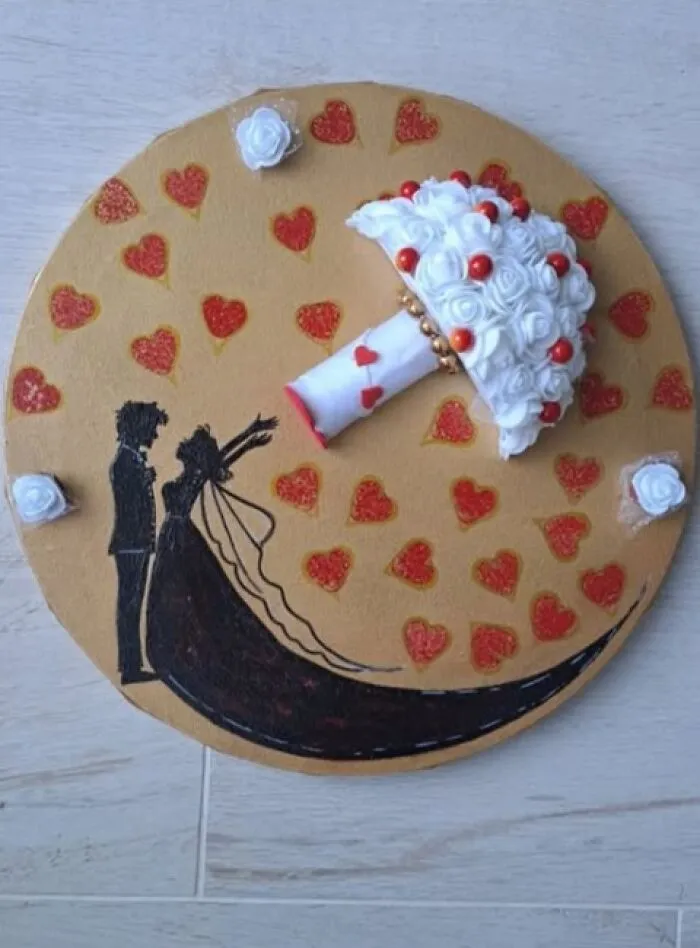 A handmade wedding-themed art project featuring a 3D white rose bouquet and a silhouette of a couple.