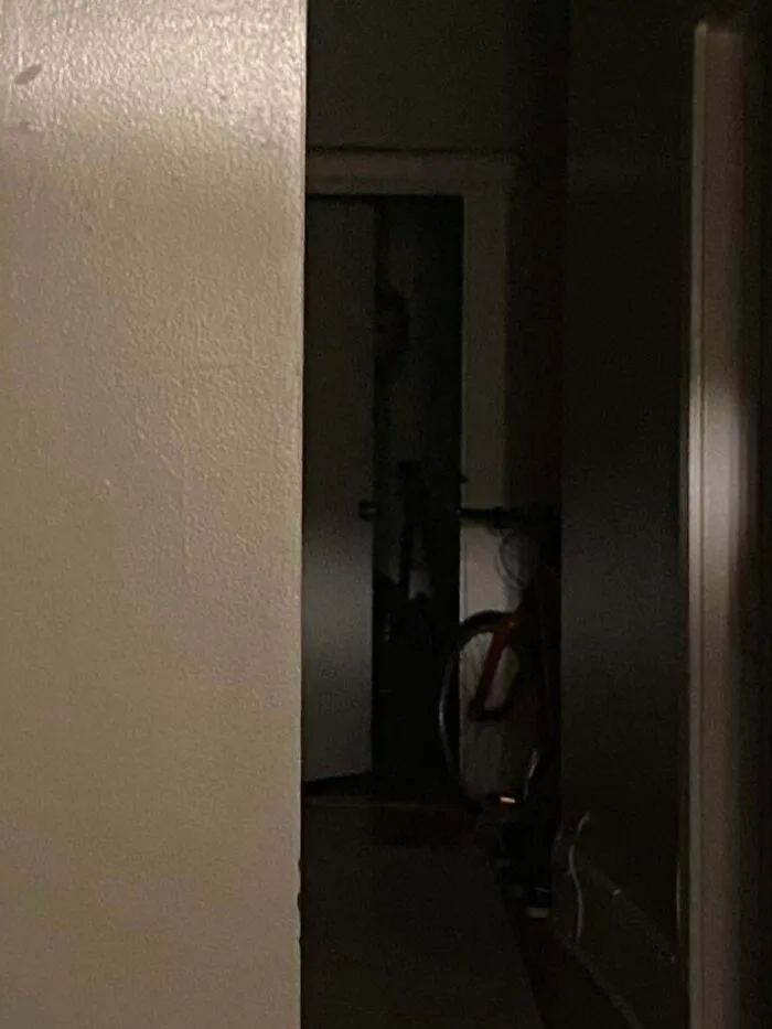 Creepy photos showing a shadowed silhouette peeking from a dark doorway down a hallway.