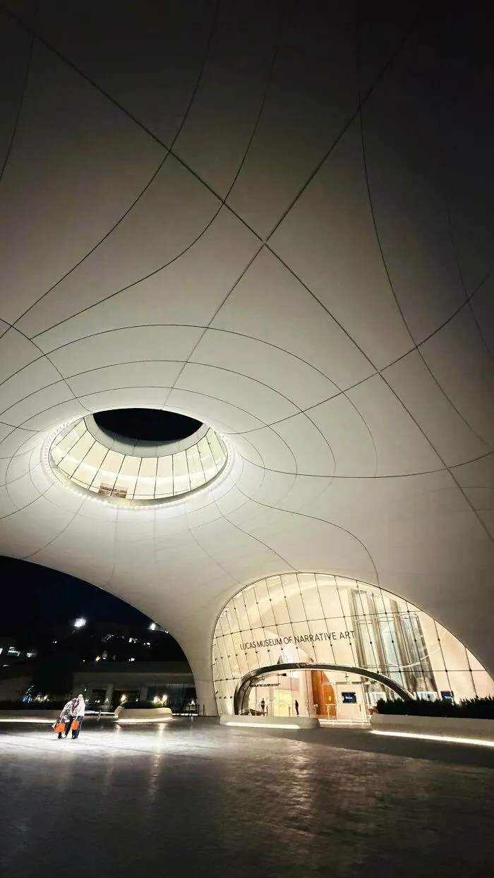 Futuristic curved white building lit at night, an architectural masterpiece of modern design
