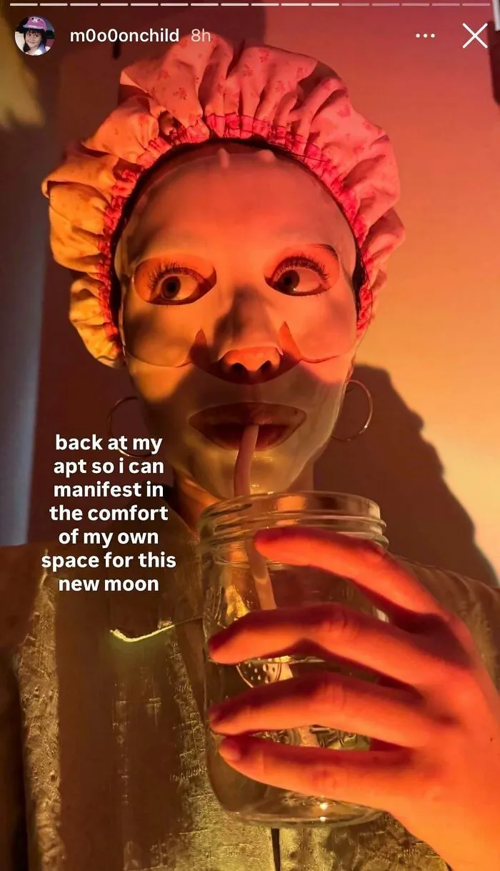 Woman wearing a facial mask drinking from jar under warm lighting for skincare influencer