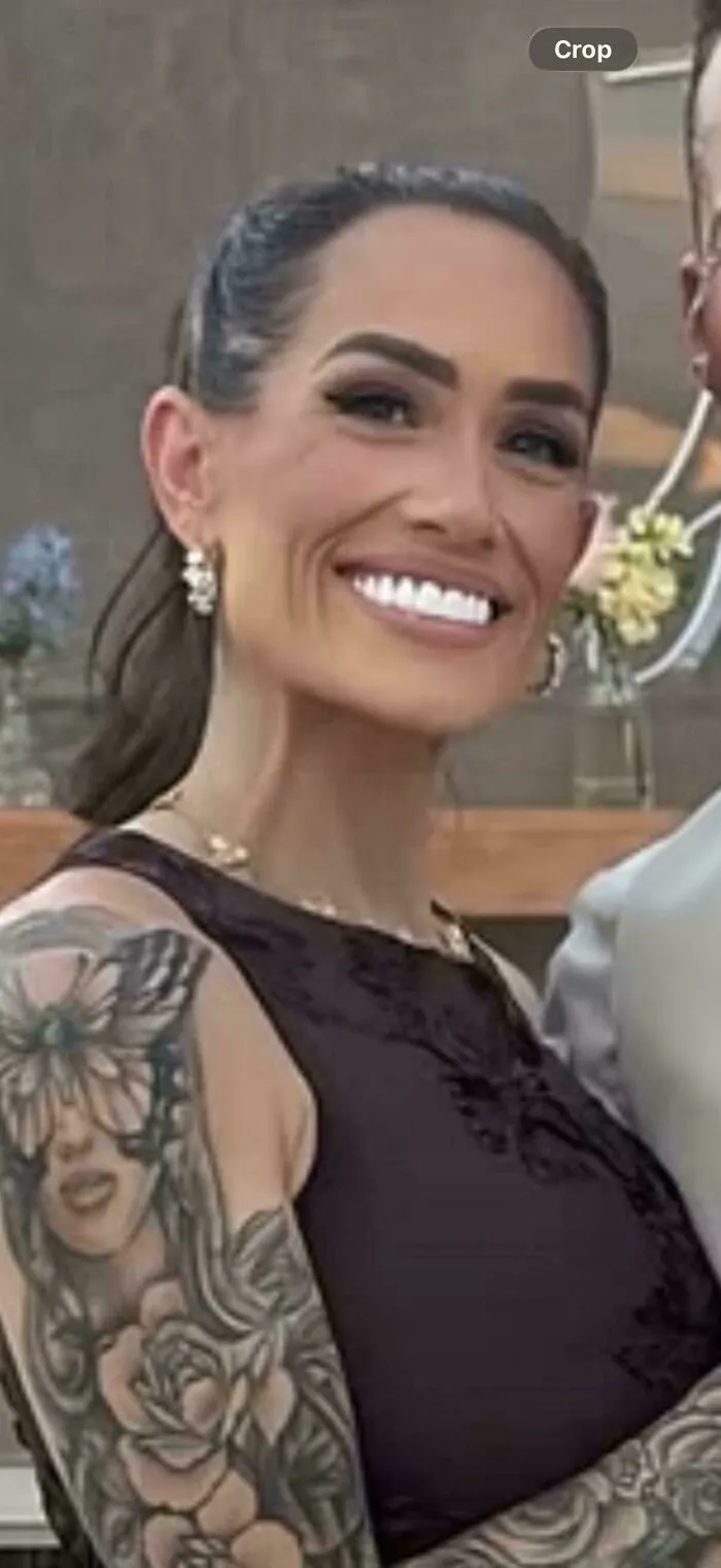 Smiling woman with tattoos and makeup posing indoors