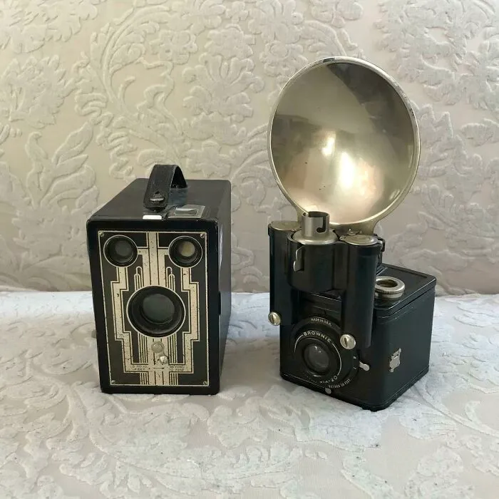 Antique Brownie box cameras with flash reflectors on a textured background