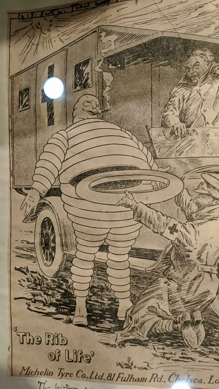 Historical cartoon showing Michelin Man sculpture with the rib of life tire theme