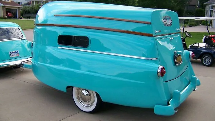 Rare historical photo of a vintage turquoise caravan trailer attached to a classic car