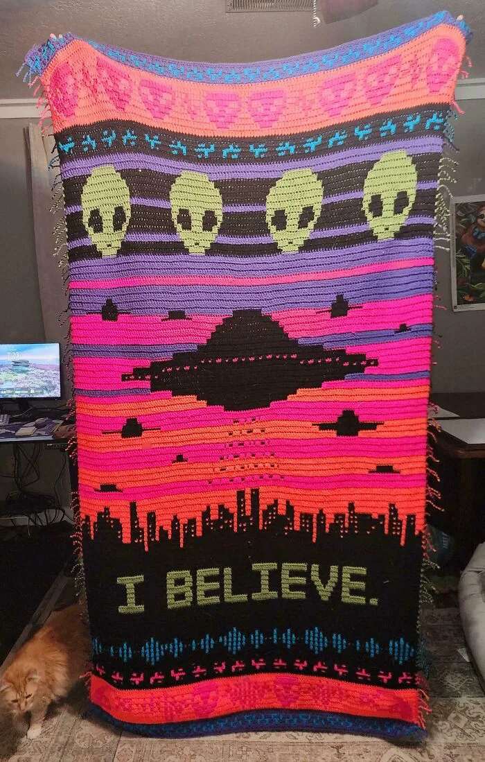 Colorful crochet blanket with aliens, UFO, and cityscape with I believe text