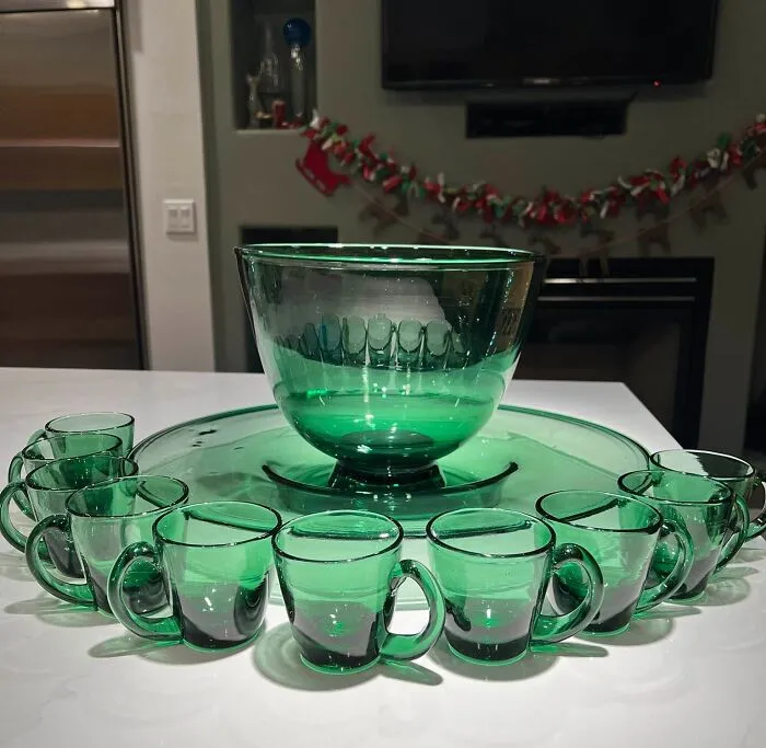 Green glass punch bowl set with matching cups arranged on table