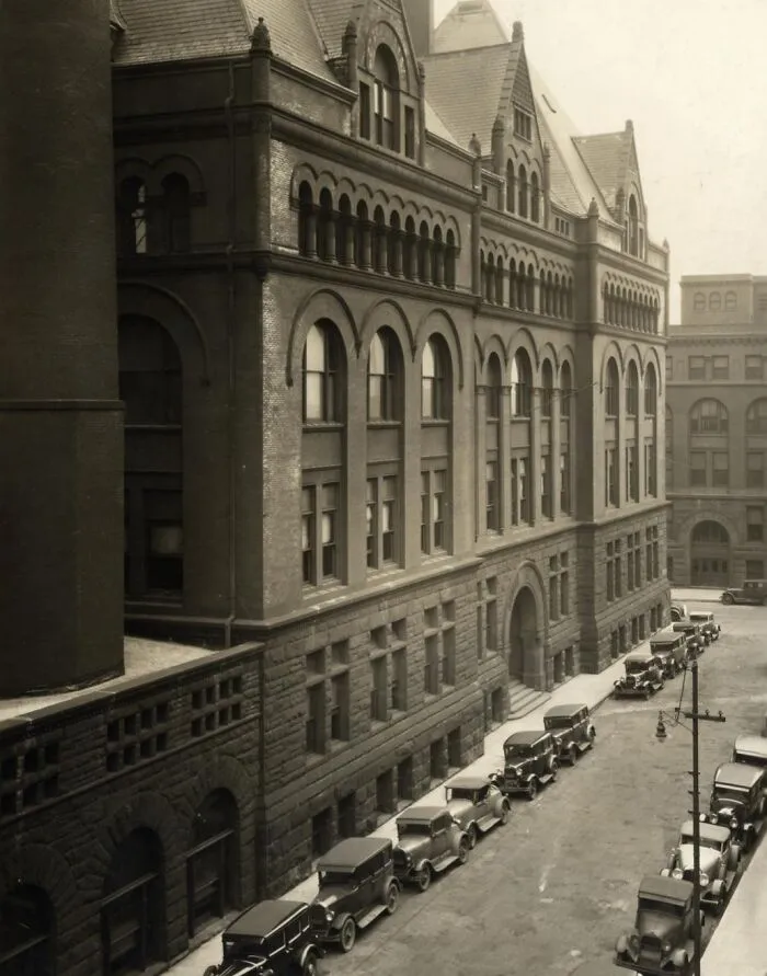 Rare historical street view photo of early 20th century cars parked alongside a large brick building
