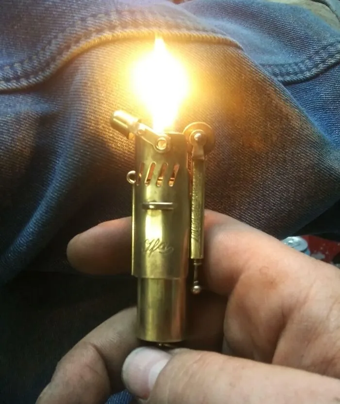 Vintage rare historical photo of a hand holding a lit antique brass lighter