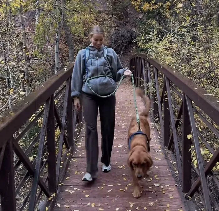 Woman walking dog on bridge in autumn nature scene, influencer outdoor lifestyle