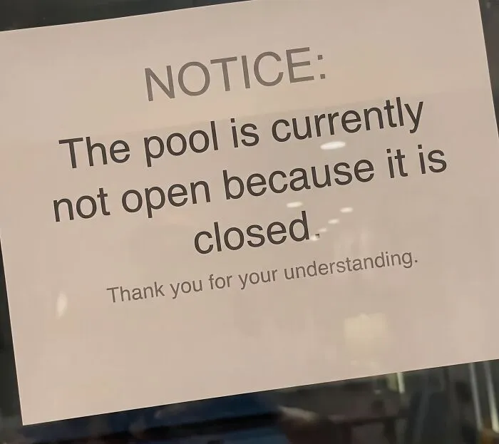 Notice sign humorously explaining pool is closed because it is not open